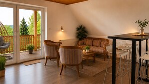 Una sala de estar acogedora con un sofá, dos sillones, una mesa de centro y un comedor con taburetes.