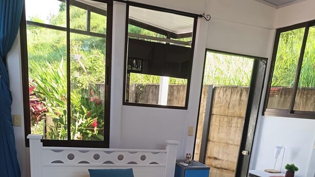 A bedroom with a bed, a nightstand, a dresser, and a window with a view of greenery. - Cute studio with AC near Chaman beach Uvita Puntarenas (Uvita)