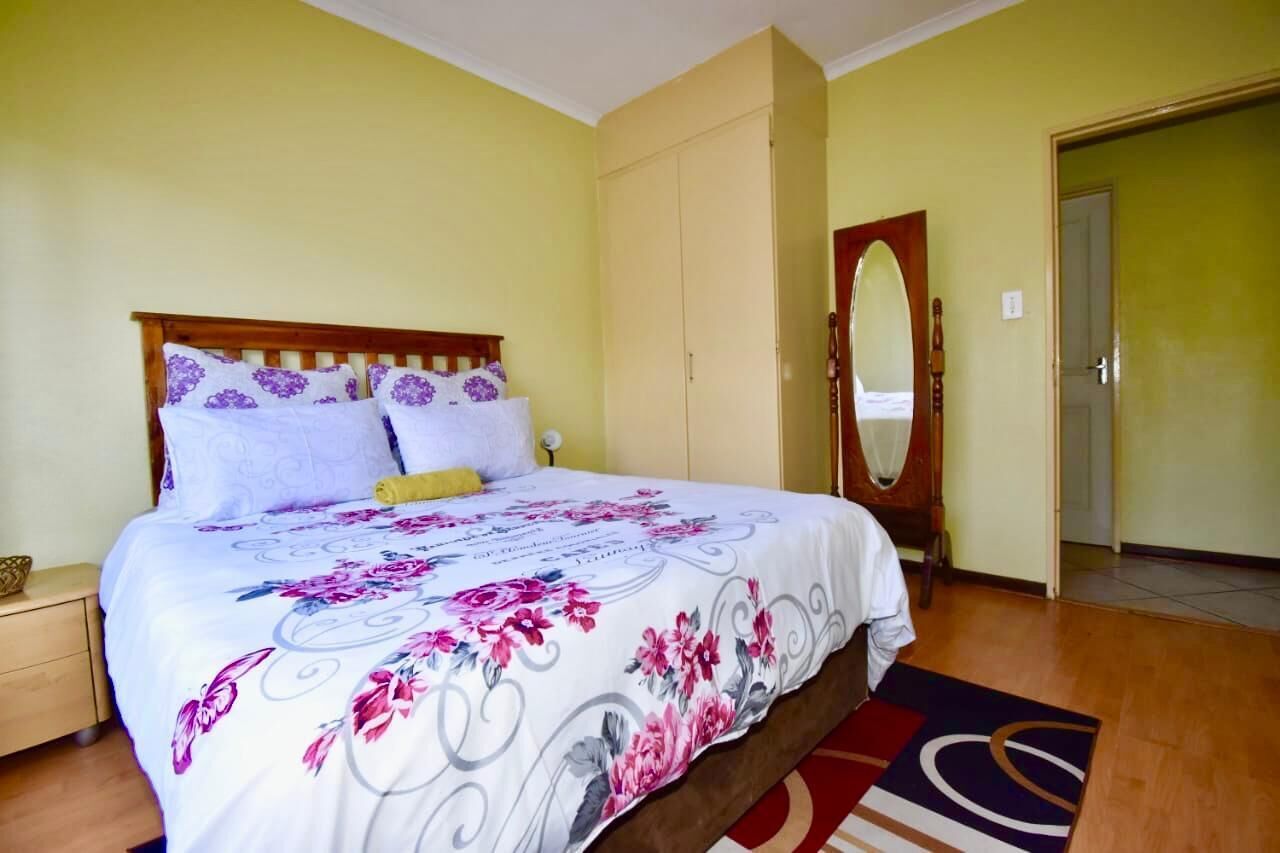 Un dormitorio con una cama, una mesita de noche de madera, un armario y un espejo.