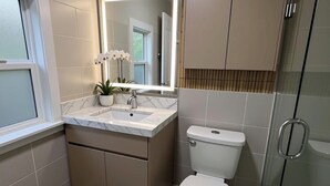 Un baño moderno con cabina de ducha de vidrio, lavamanos de mármol y un inodoro.