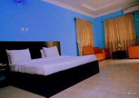 Quarto de hotel com cama grande, sofá e cortinas.