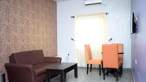 Un salon avec un canapé, une table basse, un téléviseur et une fenêtre avec des rideaux.
