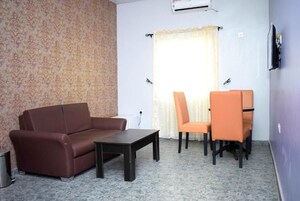 Sala de estar com sofá, mesa de centro, televisão e janela com cortinas.