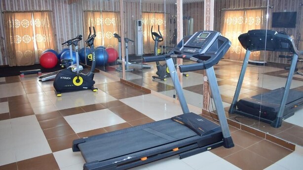Une salle de sport équipée de tapis de course, de ballons d’exercice et d’un mur recouvert de miroirs.