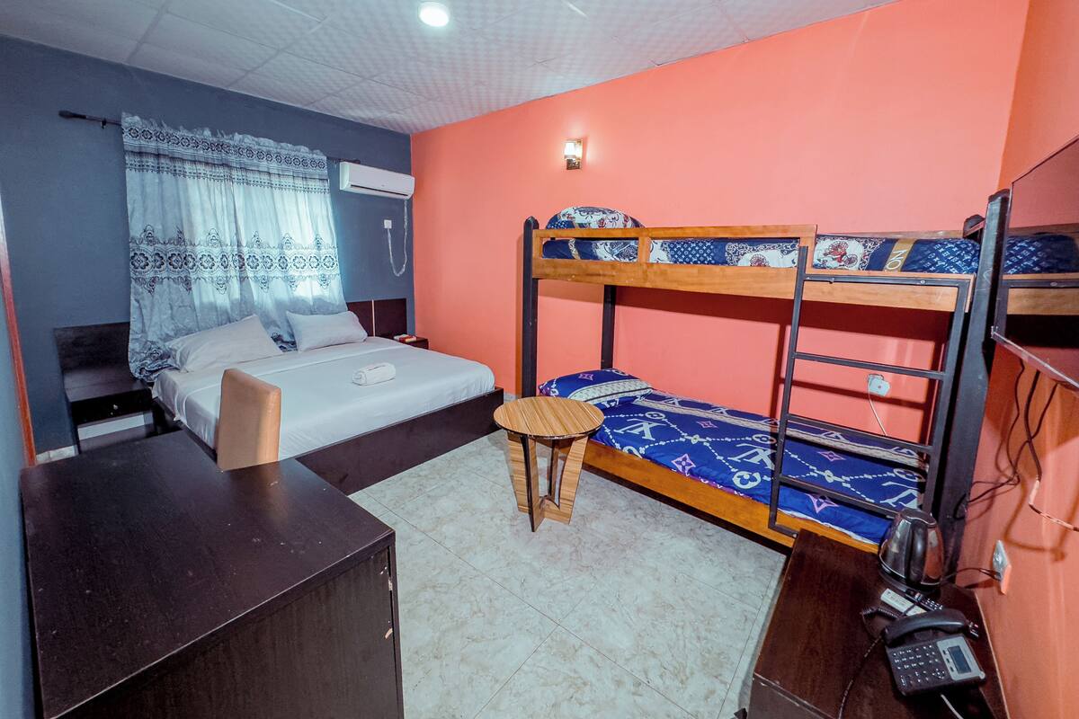 Een kamer met een stapelbed, een bureau, een stoel, een kleine tafel en een telefoon.