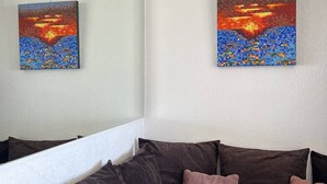 En stue med en mørkebrun sofa, to puder og to billeder på væggen.