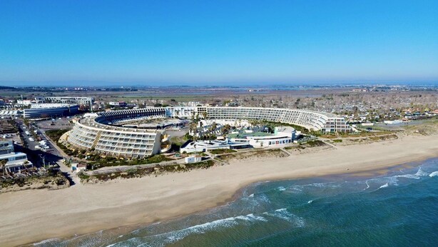 Un hotel sulla costa con un edificio curvo, accesso diretto alla spiaggia e vista sull'oceano.