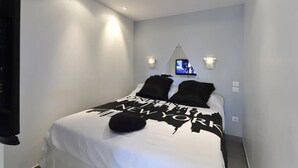 Una camera da letto con un letto, una TV montata a parete e due luci a parete.