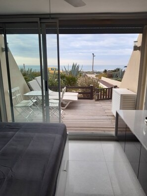 Ein Balkon mit Blick auf den Strand, einem Tisch, Stühlen und einem Bett.