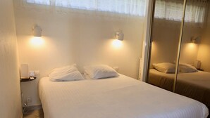 A bedroom with a bed, two bedside lamps, a mirror, and a window with curtains. - SESAME - Apartment Port Ambonne PA122 - Luxe - 4 people (AGDE)