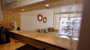 A kitchen with a coffee machine, a sink, and a countertop. There is a seating area with a sofa and cushions. - SESAME - Apartment Port Ambonne PA122 - Luxe - 4 people (AGDE)