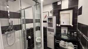 A modern bathroom with a glass-enclosed shower, a toilet, a vanity with a mirror, and a cabinet with toiletries. - ZEN - Port Ambonne Apartment  PA311 - Luxury - 2 people (AGDE)