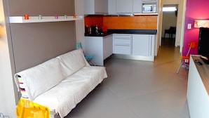 Un espace de vie compact comprenant un coin cuisine, un canapé et un coin repas.