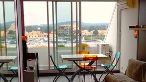 Un balcon avec une table et des chaises, un canapé et une vue sur des immeubles et une marina.