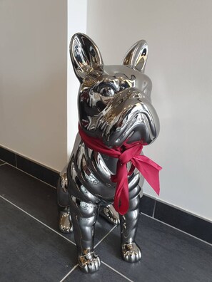 Eine Metallskulptur eines Hundes mit einem roten Band.