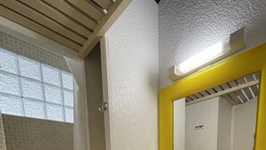 Um banheiro com pia amarela, espelho e chuveiro.