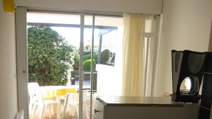 Cozinha compacta com pia, fogão e área de refeições com mesa e cadeiras.