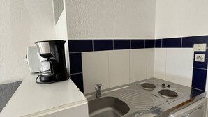 Uma cozinha compacta equipada com cafeteira, pia e fogão.