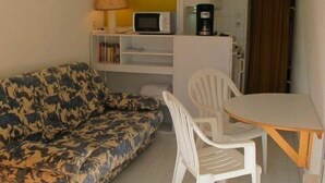 A small living area with a sofa, a table with chairs, a microwave, a coffee maker, and a cabinet. - Port Nature Studio 22 - 2 people (AGDE)