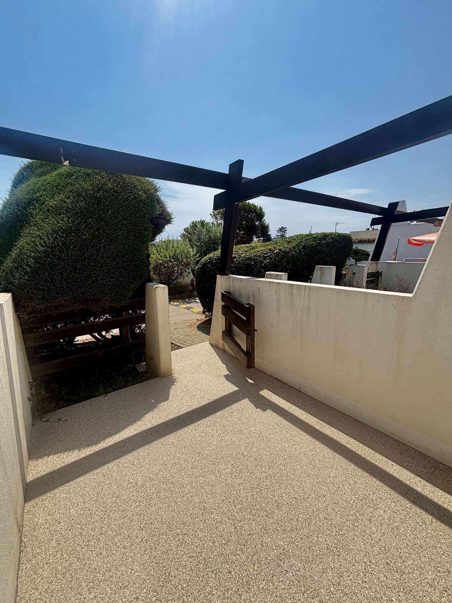 Eine Dachterrasse mit einer Pergola, einer Holzbank und Blick auf den Himmel.