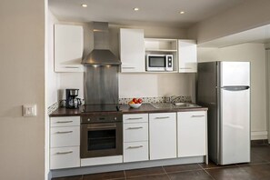 Una cocina moderna con armarios blancos, electrodomésticos de acero inoxidable y salpicadero de azulejos.