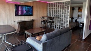 En moderne stue med sofa, fjernsyn og et TV ophængt på væggen.