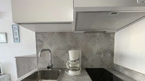 A kitchen with a stainless steel sink, a coffee maker, and a black induction cooktop. - Port Nature Studio 67 - 2 people (AGDE)