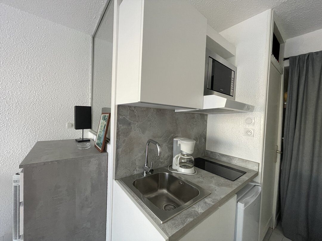Una cocina compacta equipada con microondas, cafetera y lavabo.