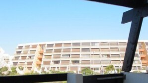 An outdoor patio with a table and chairs, a view of a building with balconies, and a wooden fence. - Port Nature Studio 67 - 2 people (AGDE)