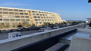A large, multi-story hotel with a modern design, featuring a prominent parking area and a water feature in the foreground. - Port Nature Studio 70 - 2 people (AGDE)