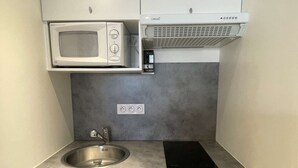 A compact kitchenette with a microwave, stove, and built-in oven. - Port Nature Studio 70 - 2 people (AGDE)