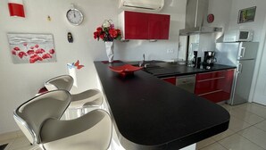Moderni keittiö, jossa on musta työtaso, punaiset kaapit ja ruostumattomasta teräksestä valmistetut kodinkoneet.