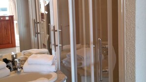 Une salle de bain avec une douche à parois de verre, un lavabo avec un miroir et des serviettes.