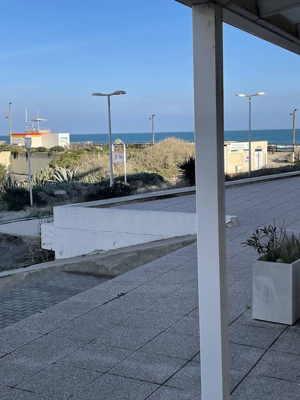Ein Küstenwanderweg mit befestigtem Weg, Straßenlaternen und Blick auf das Meer.
