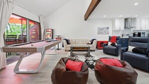 Un salon moderne avec une table de billard, des canapés en cuir, une table basse et un coin cuisine.