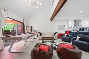 Ein modernes Wohnzimmer mit Billardtisch, Ledersofas, einem Couchtisch und einer Küchenzeile.