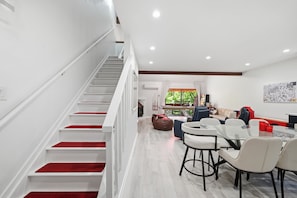 Ein modernes Interieur mit einer Treppe, einem Essbereich mit Barhocker und Blick auf Grünflächen.