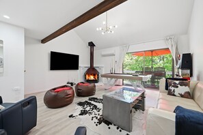 Ein modernes Wohnzimmer mit Kamin, Billardtisch und einer Couch.
