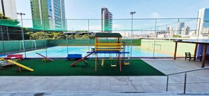 An outdoor playground with a basketball court, climbing structures, and a fenced area. - COPBV0101 - Edificio Torres do Iguatemi (Salvador)