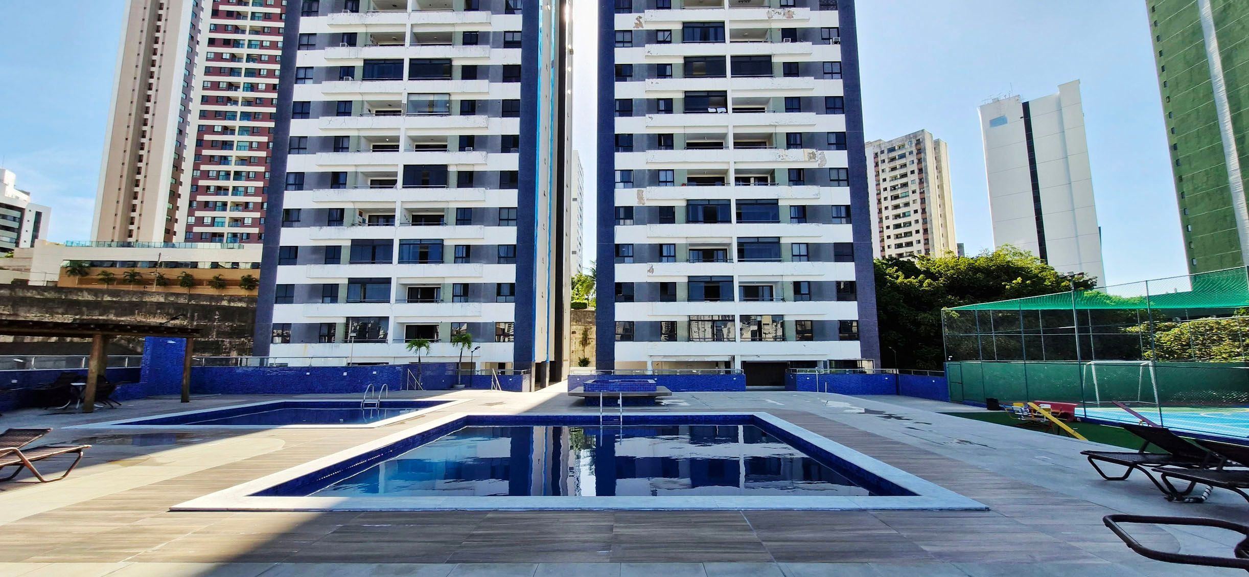 A modern apartment building with a rooftop pool area, including a swimming pool and lounge chairs.