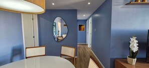 A hotel room with a dining area featuring a white table and chairs, a mirror on the wall, and a potted orchid on a side table. - COPBV0101 - Edificio Torres do Iguatemi (Salvador)