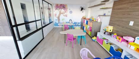 Un cuarto de juegos infantil con un ventanal grande, un mural y unidades de almacenamiento de colores.