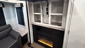 A modern living room with a fireplace, built-in shelves, and a grey sofa.
