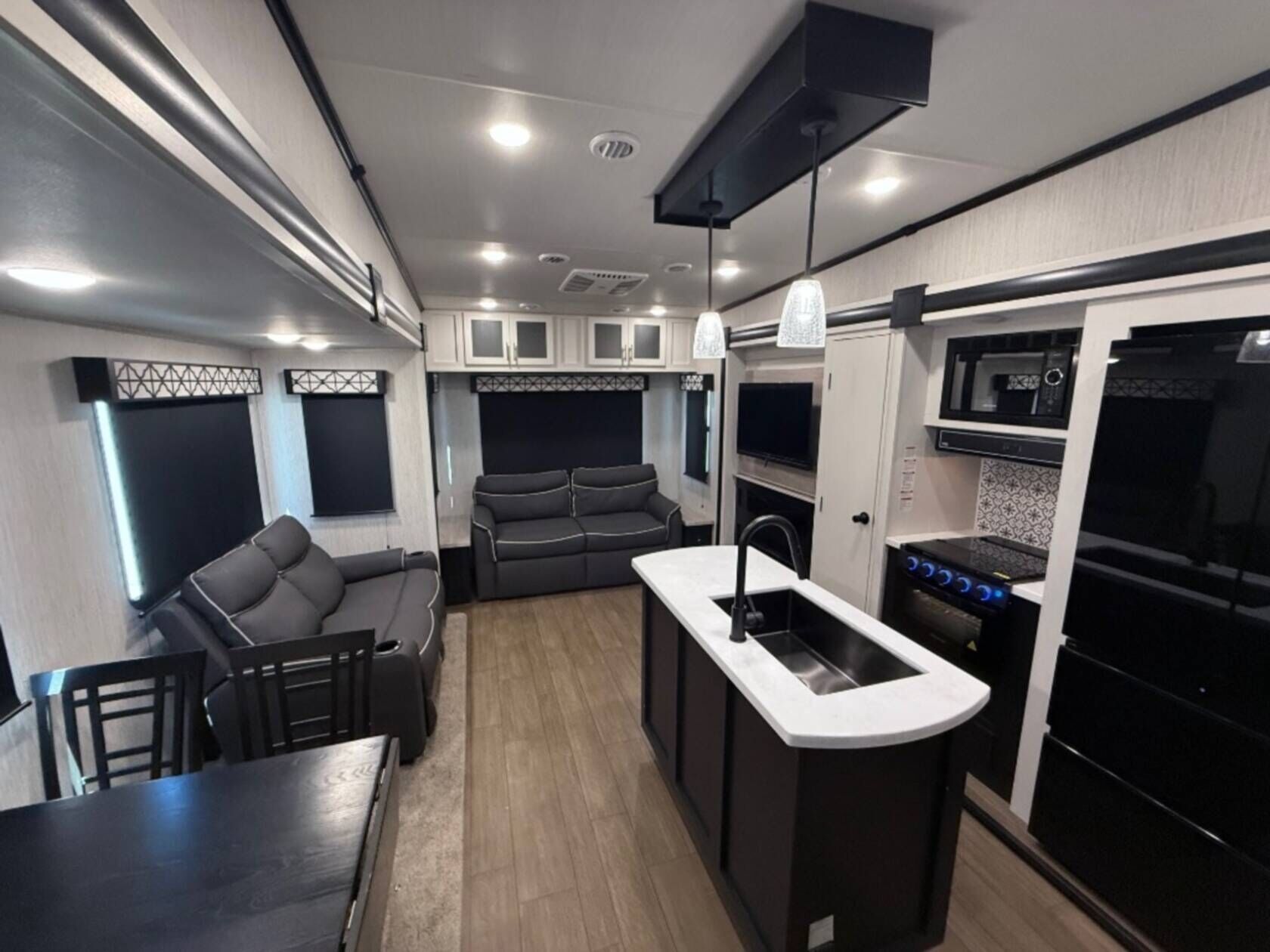 Interno di un camper compatto con angolo cottura, zona salotto e tavolo da pranzo.