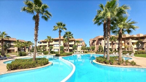 Ein Schwimmbad mit Palmen und Hotels im Hintergrund.