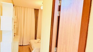Ein Schlafzimmer mit einem Bett, einem Nachttisch, einem Kleiderschrank und einer Tür zu einem anderen Raum.