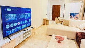 Ein modernes Wohnzimmer mit Flachbildfernseher, einer Couch, einem Couchtisch und einem Essbereich.
