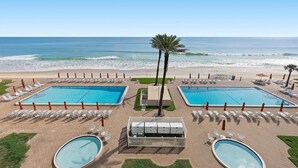 A resort pool area with two rectangular pools, a palm tree, and beach views. - Sandpiper 514 (New Smyrna Beach)