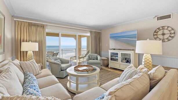 A living room with a sofa, armchairs, a coffee table, a lamp, a clock, and a painting. - Sandpiper 514 (New Smyrna Beach)