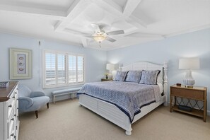 A bedroom with a bed, a nightstand, a chair, a dresser, a window, and a ceiling fan. - Sandpiper 514 (New Smyrna Beach)
